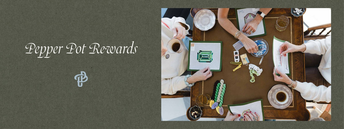 A promotional banner for 'Pepper Pot Rewards' featuring a dark olive green textured background on the left with white text and a logo, and a top-down photo of people gathered around a wooden table with needlepoint canvases and supplies. 