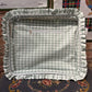 Green checkered fabric tray with ruffled edge on a patterned surface