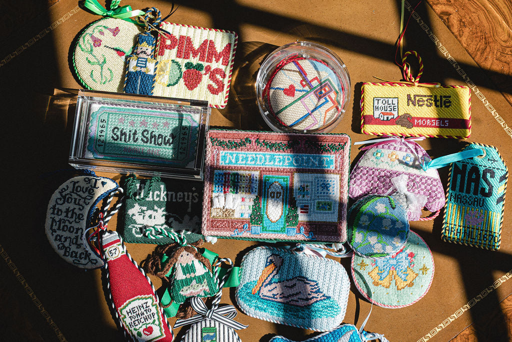 Collection of finished needlepoint ornaments on a wooden surface.  | The Pepper Pot Barrington, IL 