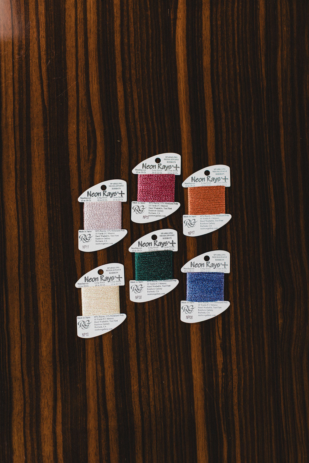 Colored threads by Neon Rays on a wooden surface.  | The Pepper Pot Barrington, IL 
