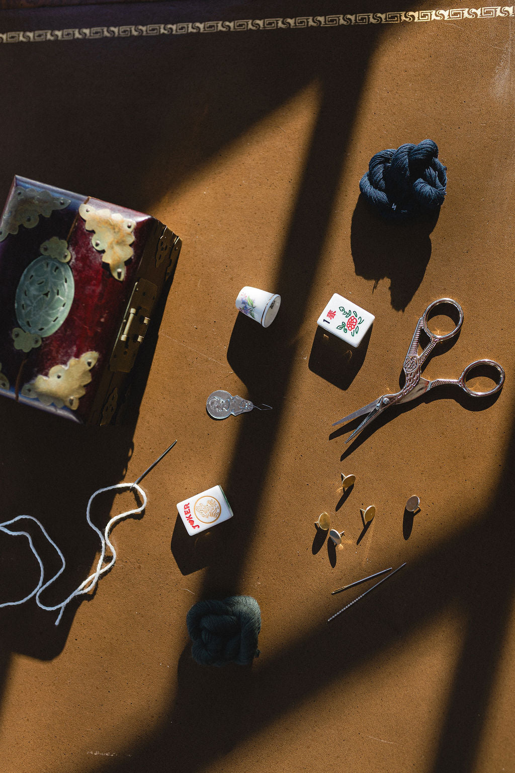 Vintage sewing items including scissors, thread, and fabric on a brown surface.  | The Pepper Pot Barrington, IL 