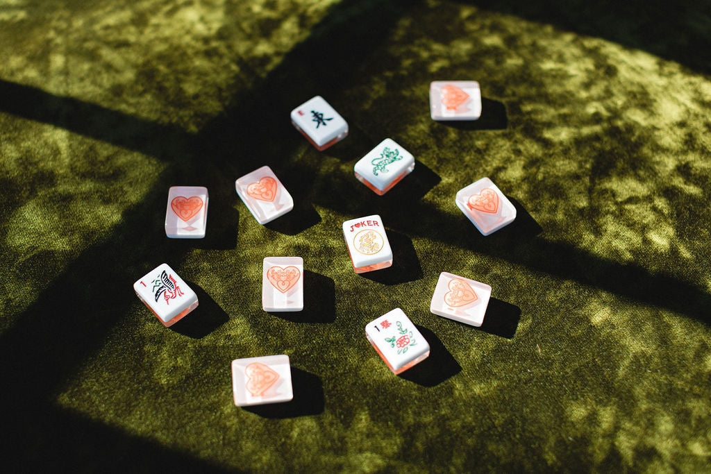 Set of mahjong tiles with floral designs on a green textured surface.  | The Pepper Pot Barrington, IL 
