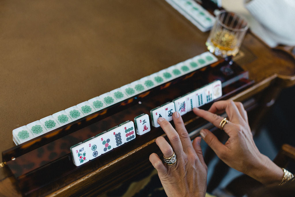 Close-up of hands playing mahjong with tiles on a table.  | The Pepper Pot Barrington, IL 