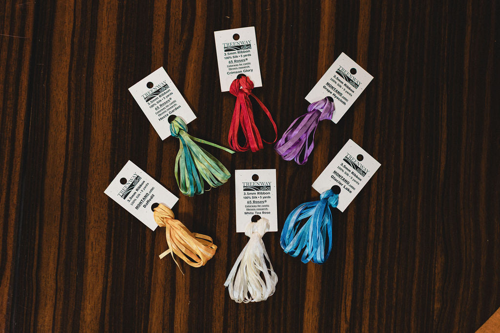 Set of colorful threads with labels on a wooden surface.  | The Pepper Pot Barrington, IL 