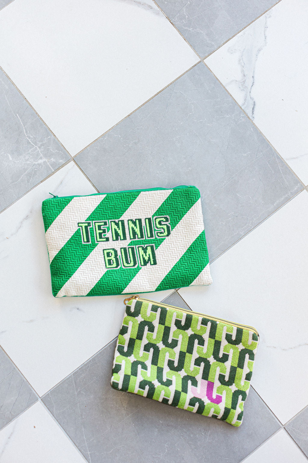 Two green needlepoint pouches with text on a gray and white tiled floor.  | The Pepper Pot Barrington, IL 
