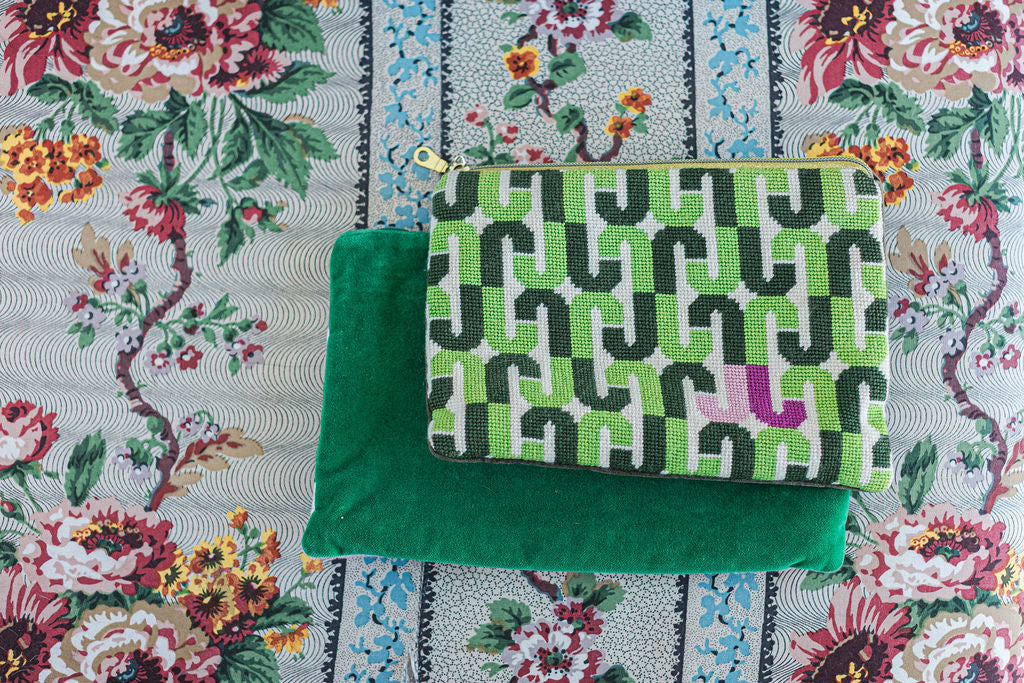 Green patterned needlepoint or cross stitched pouch on a floral fabric background. | The Pepper Pot, Barrington, IL