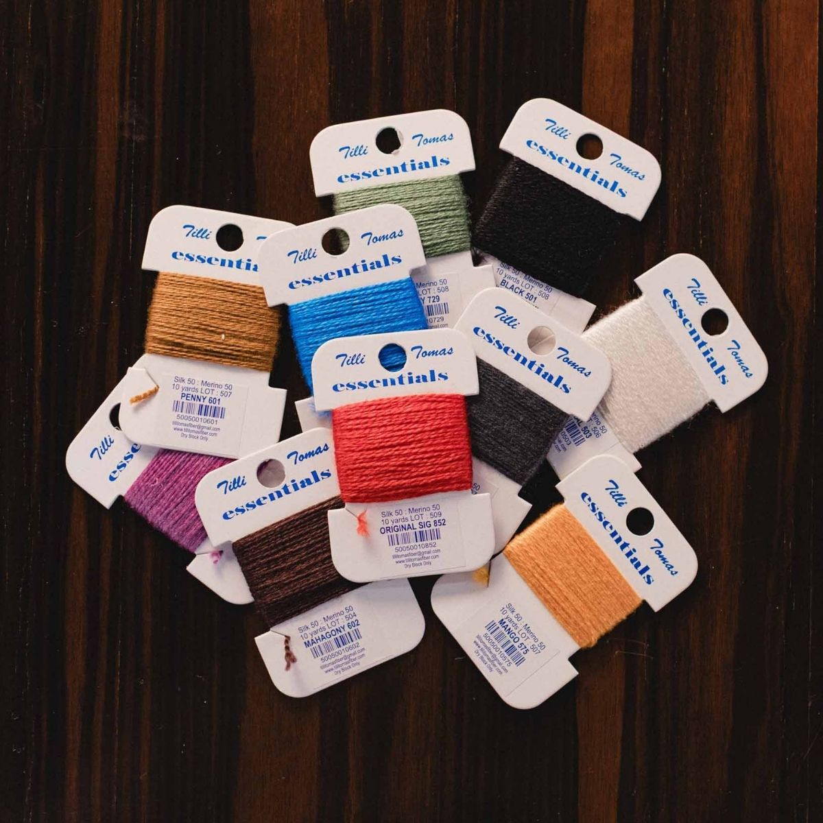Collection of embroidery floss packages with labels on a wooden surface