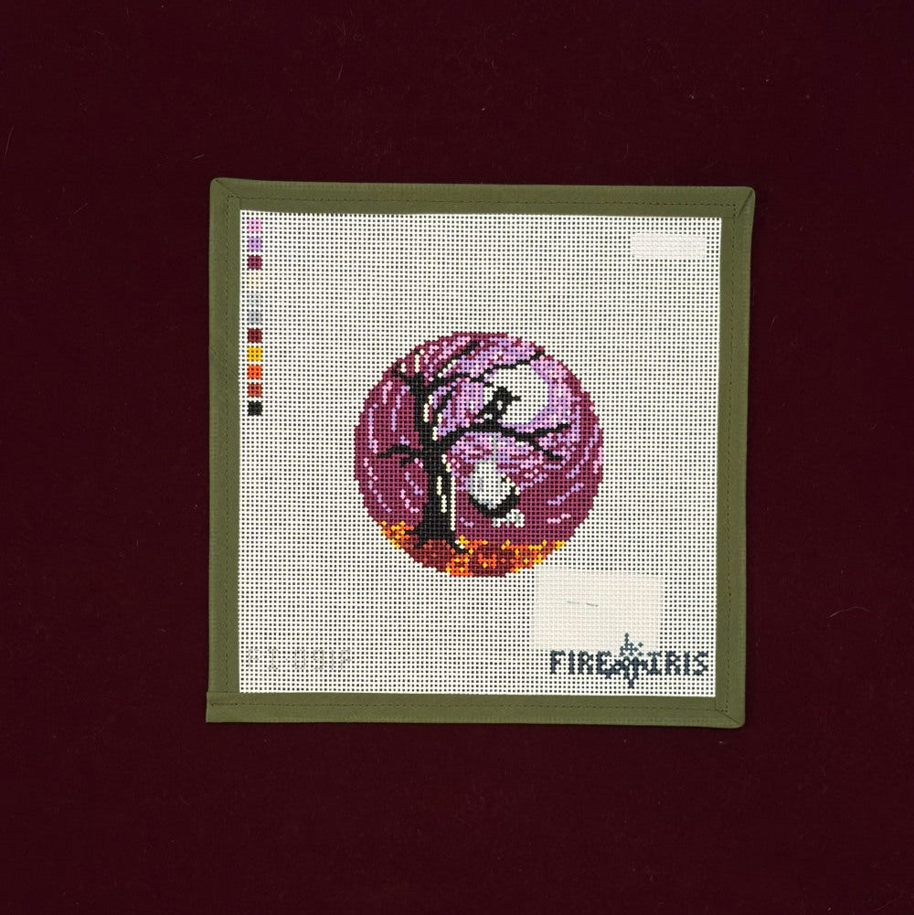 Needlepoint canvas design of a tree with pink flowers in a green frame on a dark background