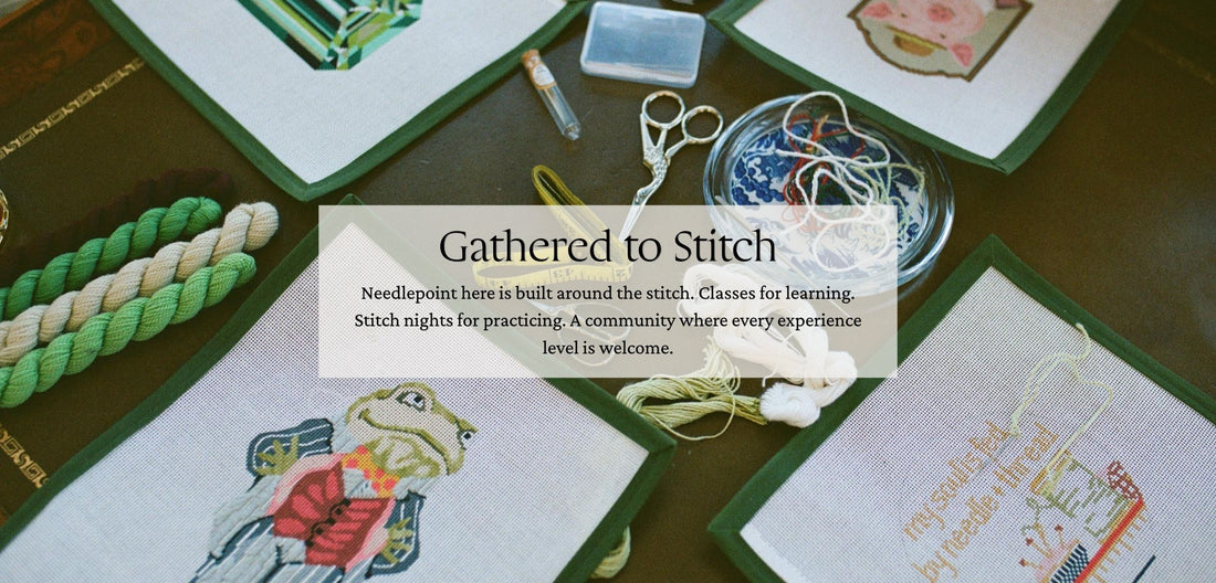 Needlepoint materials and tools on a table with 'Gathered to Stitch' text overlay. Needlepoint here is built around the stitch. Classes for learning. Stitch nights for practicing. A community where every experience level is welcome.