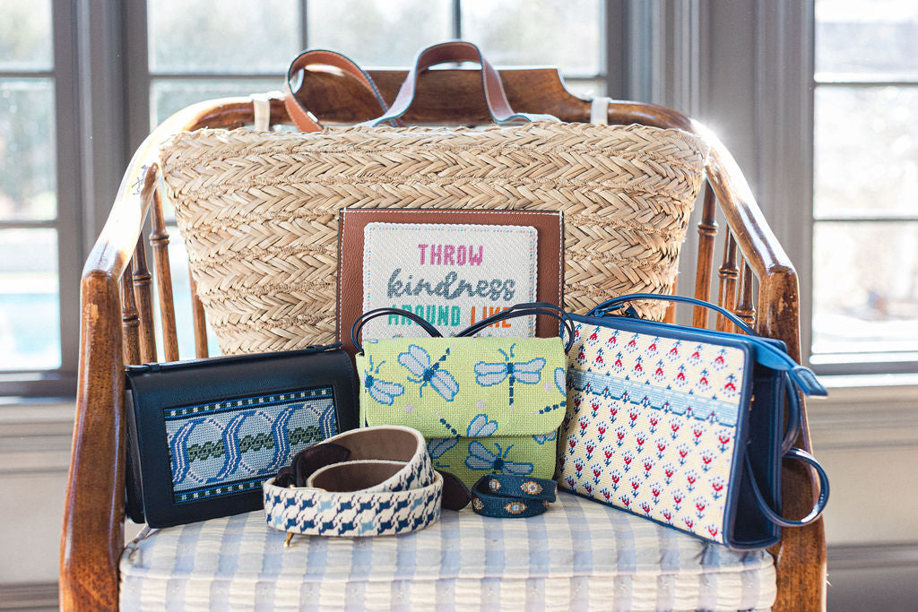 Collection of handmade needlepoint handbags and a framed quote on a wooden chair with a window background.  | The Pepper Pot Barrington, IL 