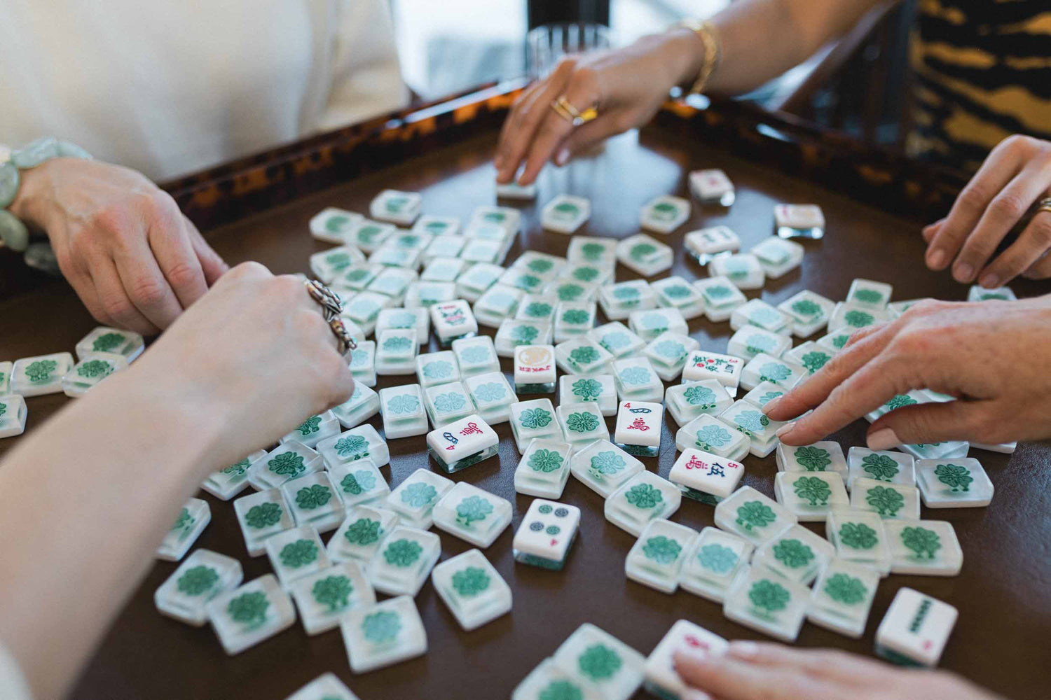 People playing a game of Mahjong with tiles on a table. The Pepper Pot | Needlepoint and Mahjong Specialty Store in Barrington, IL