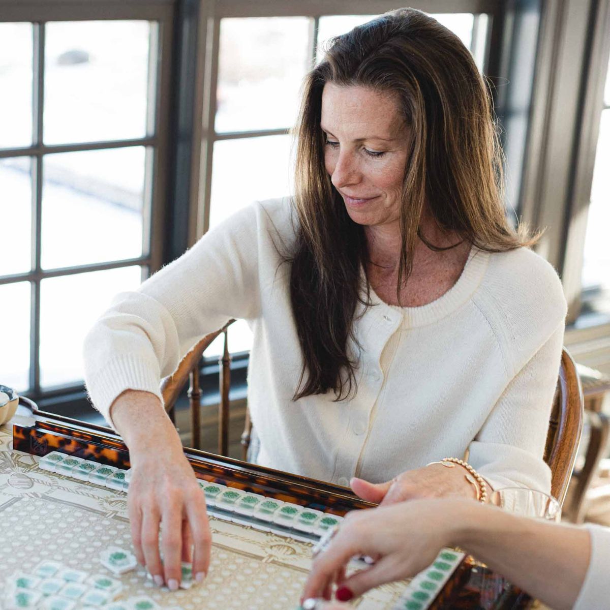 Woman playing american mahjong with another person in a cozy room in Barrington, IL. 