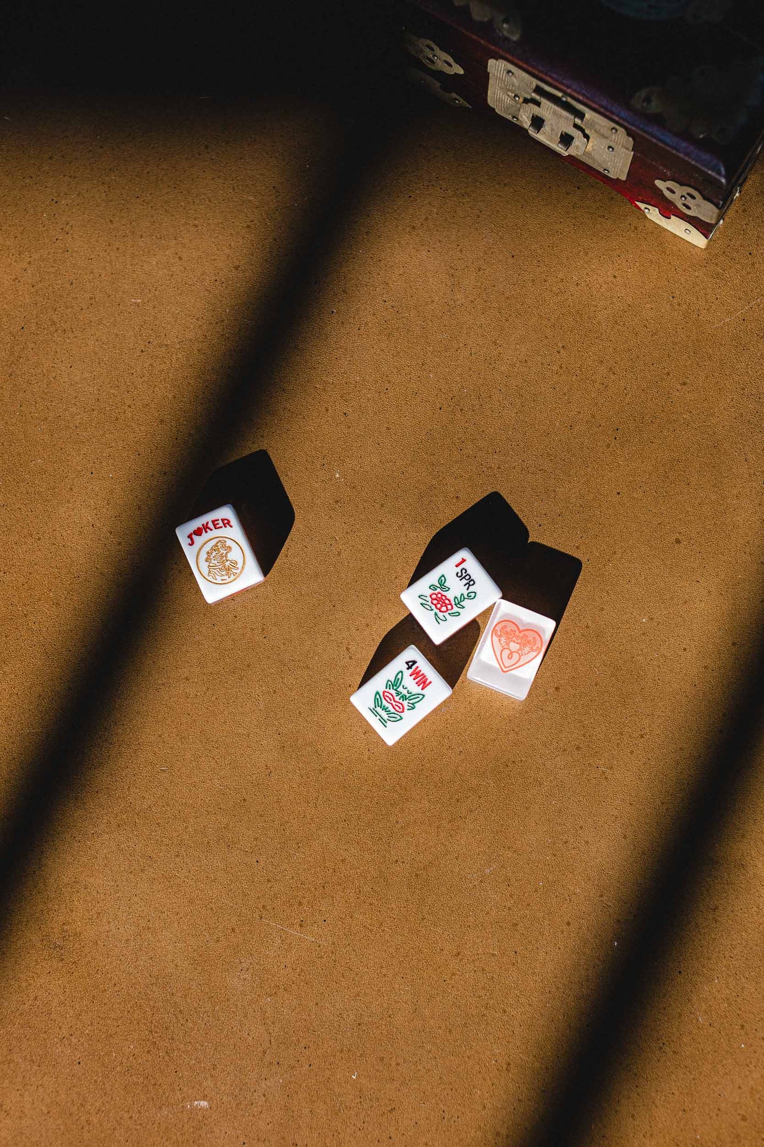 Four mahjong tiles on a brown surface with a vintage antique box in the background. | The Pepper Pot, Barrington, IL