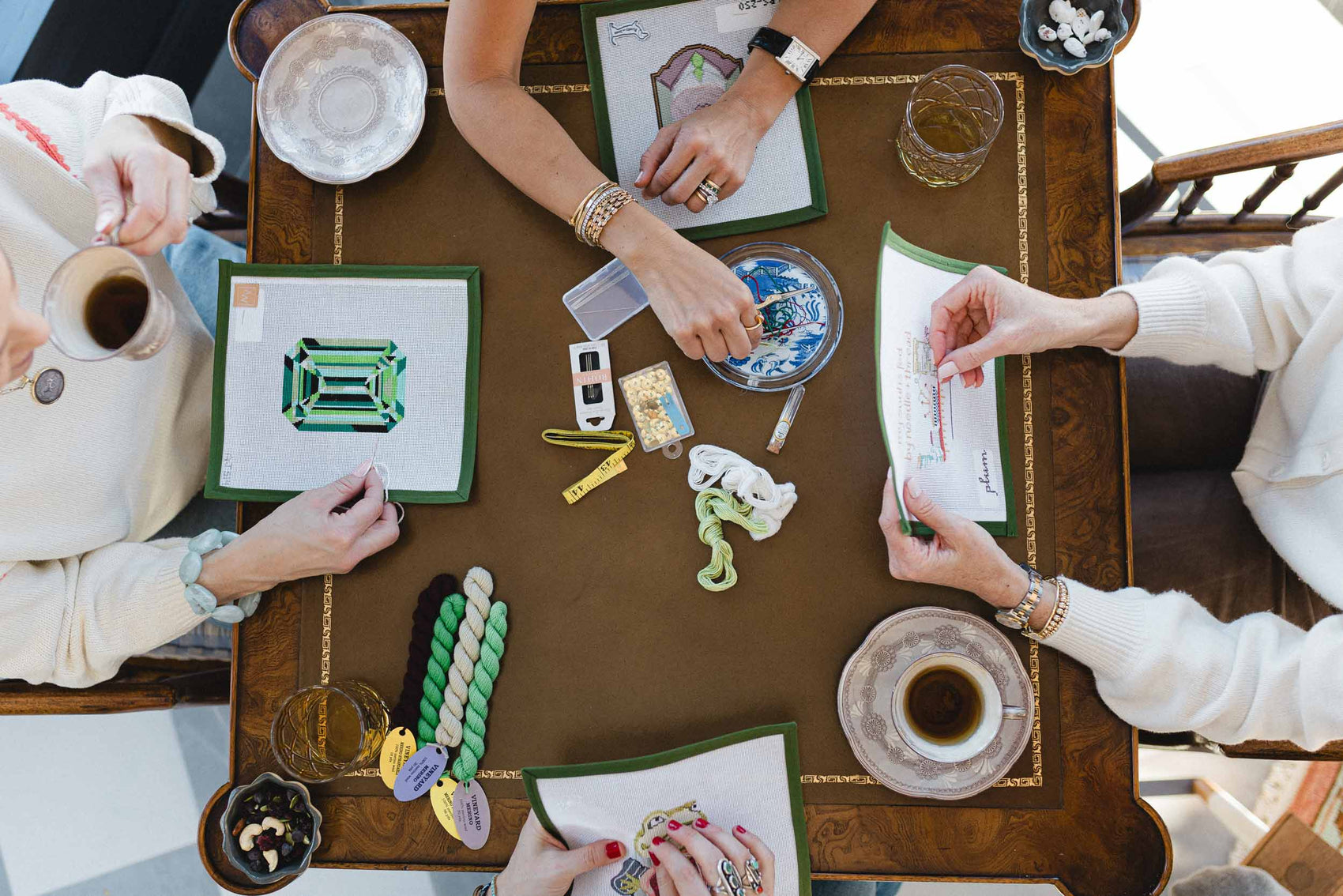 People around a table with needlepoint craft supplies, hand painted needlepoint canvases, works in progress, and decorative items. | The Pepper Pot, Barrington, IL