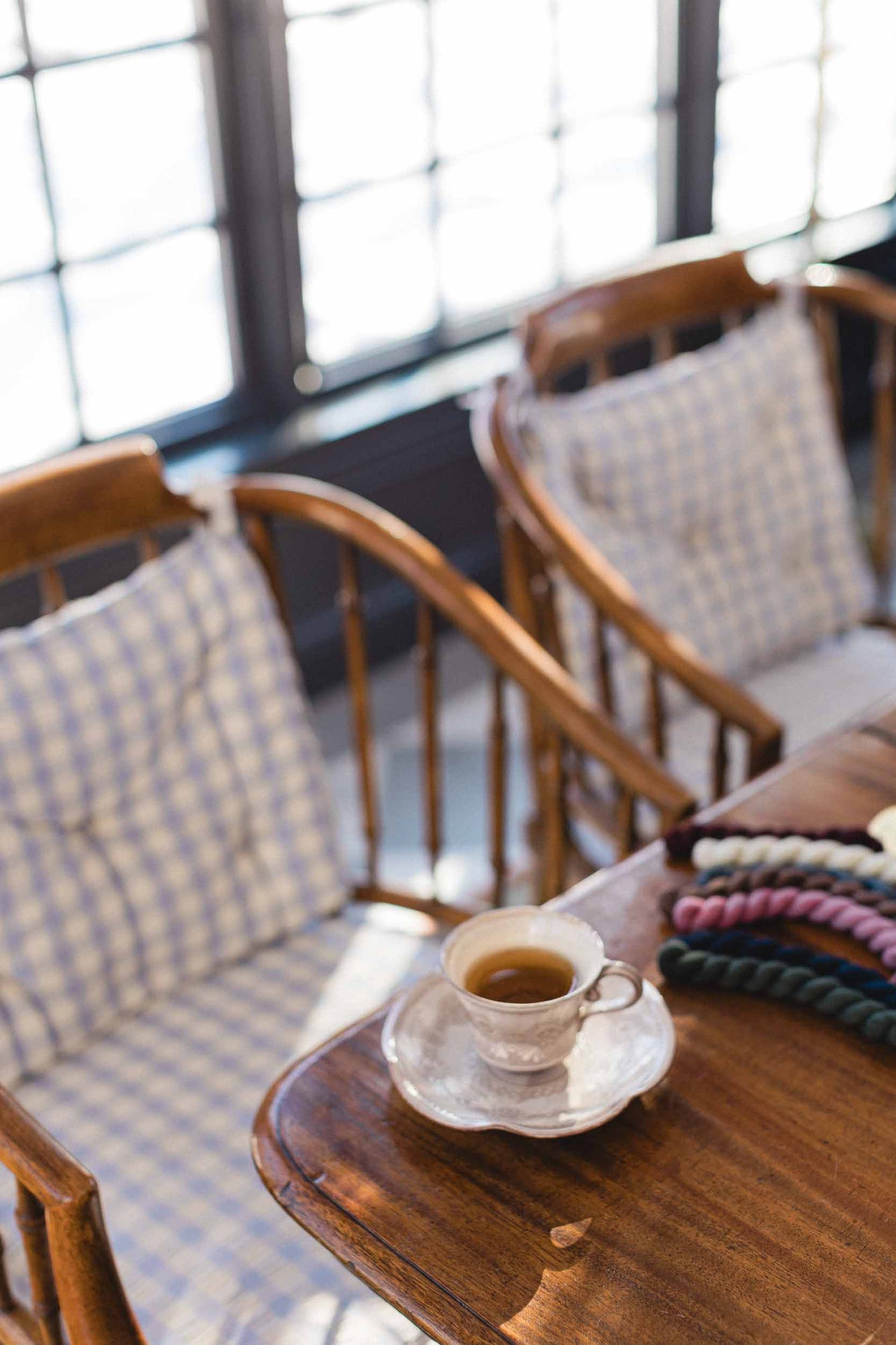 Café setting with wooden chairs and a table with a cup of coffee.
