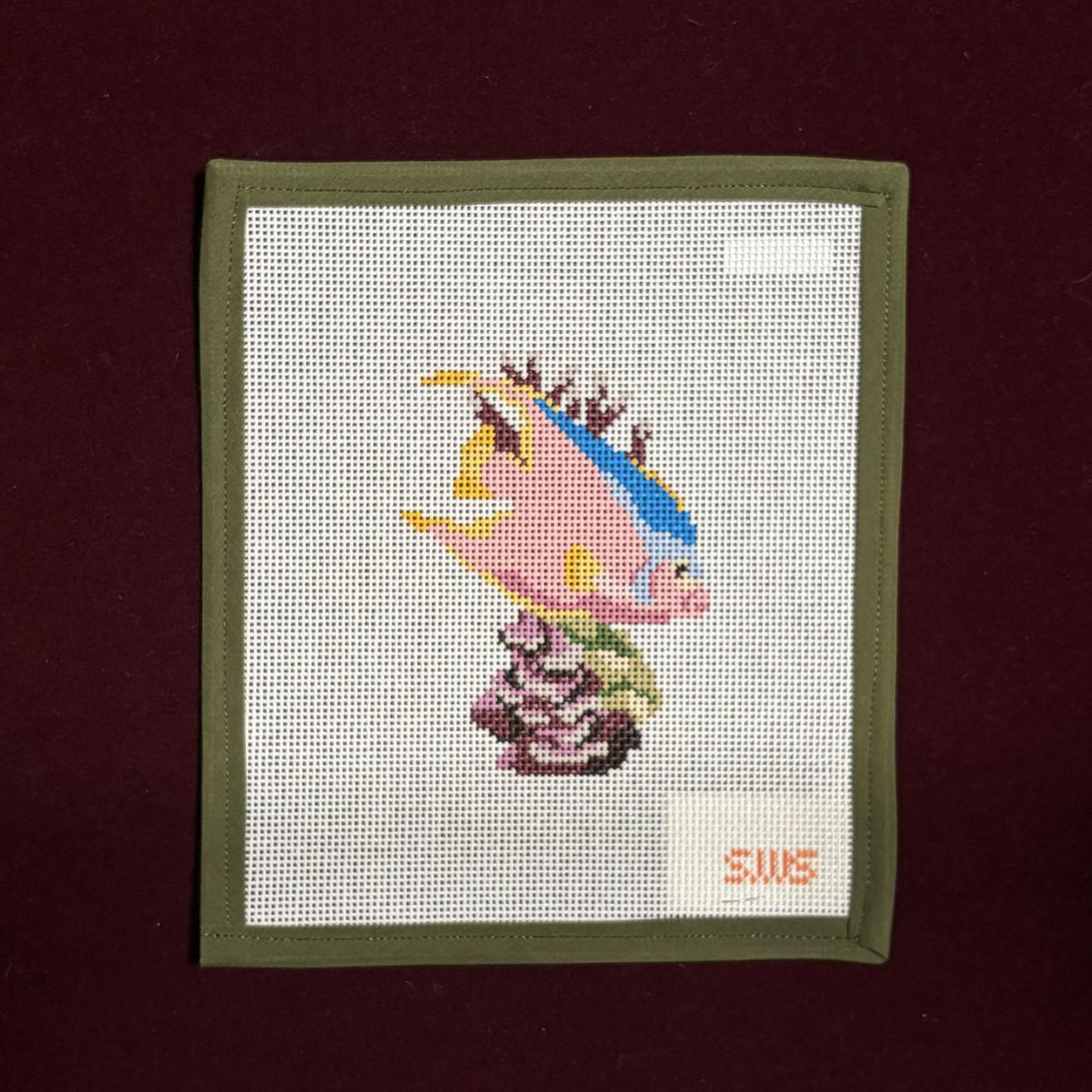 Needlepoint Canvas design of a pink and blue tropical saltwater fish swimming amongst corral and sea plants. 