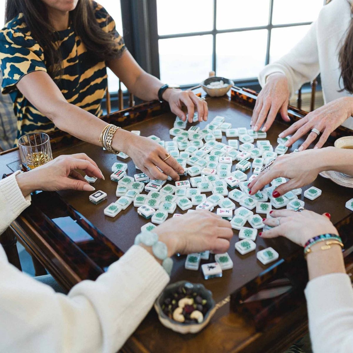 People playing a game of American Mahjong with tiles on a wooden table at The Pepper Pot in Barrington IL