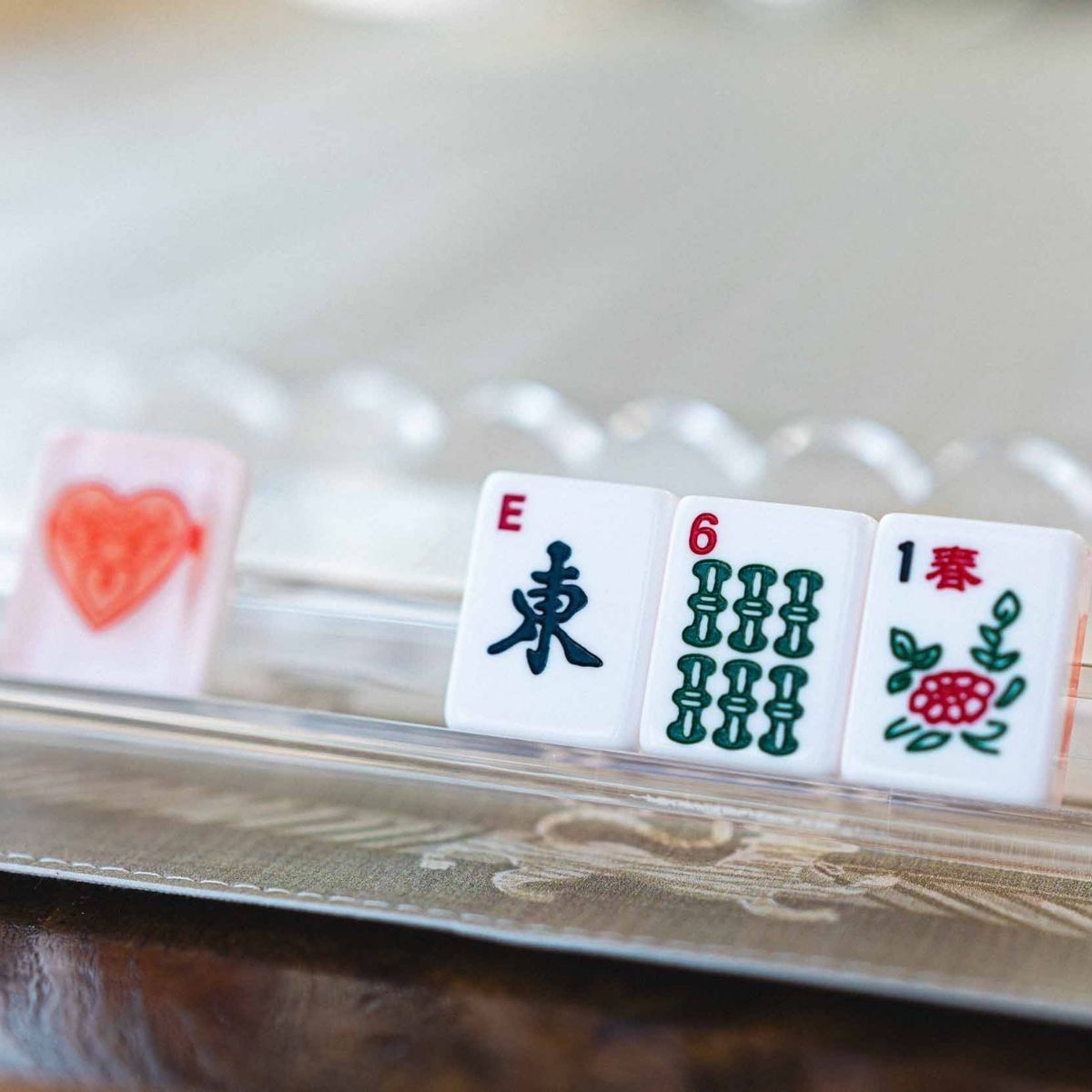 Close-up of a set of Mahjong tiles with various symbols and numbers on a reflective surface at The Pepper Pot in Barrington IL