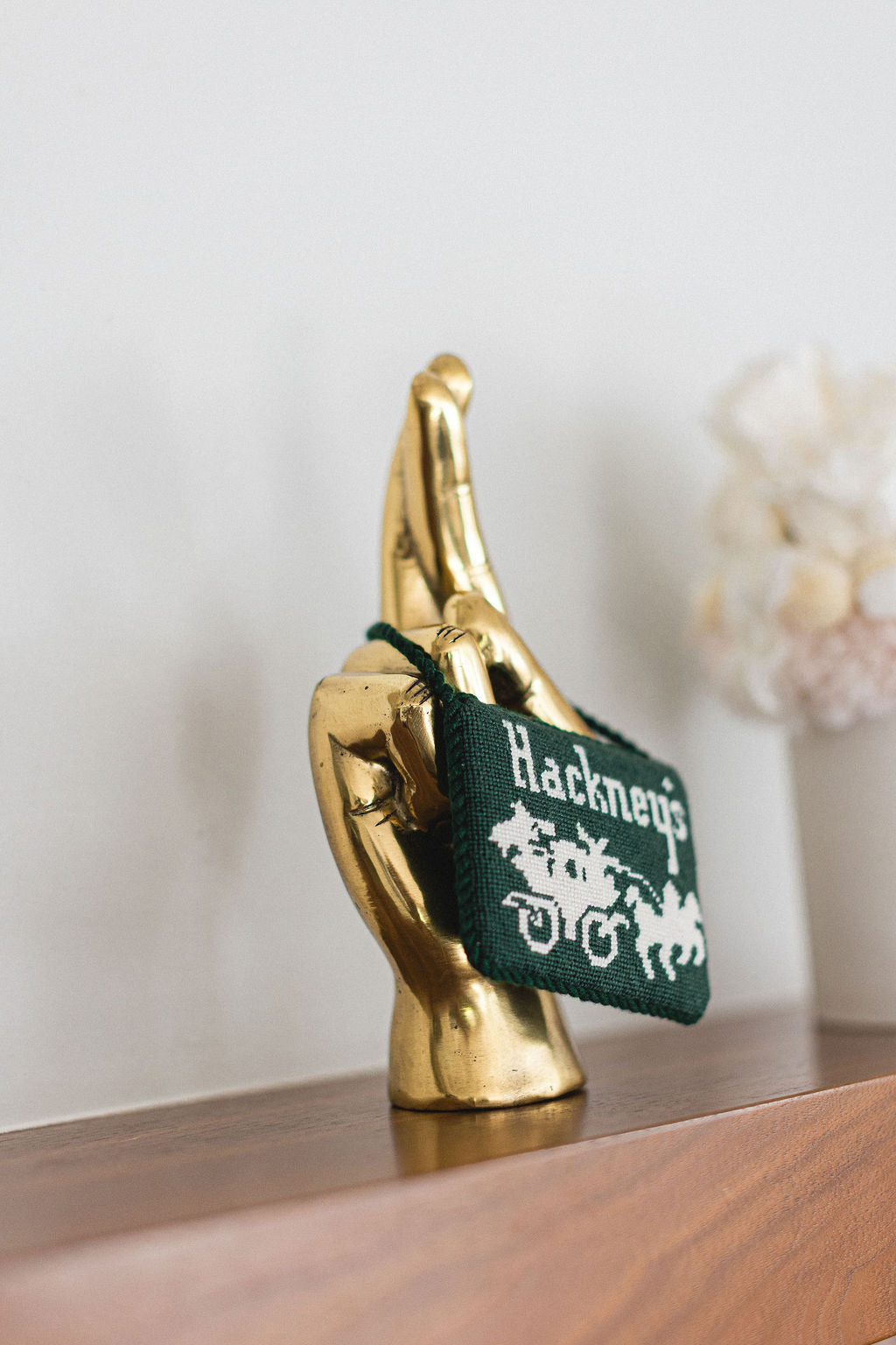 Gold hand holding a green bag with 'Hackney's' branding on a wooden surface.  | The Pepper Pot Barrington, IL 