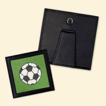 Completed soccer ball needlepoint project with a black frame for displaying