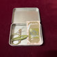 Inside view of the tin box with mini scissors, tapestry needles and a magnetic needle minder inside. 