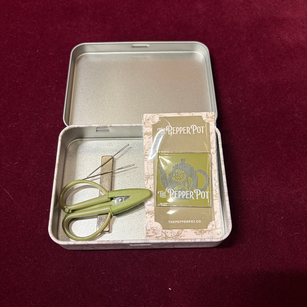 Inside view of the tin box with mini scissors, tapestry needles and a magnetic needle minder inside. 
